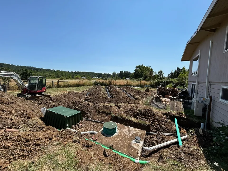 Septic tank, treatment unit, and drain field under construction beside a home